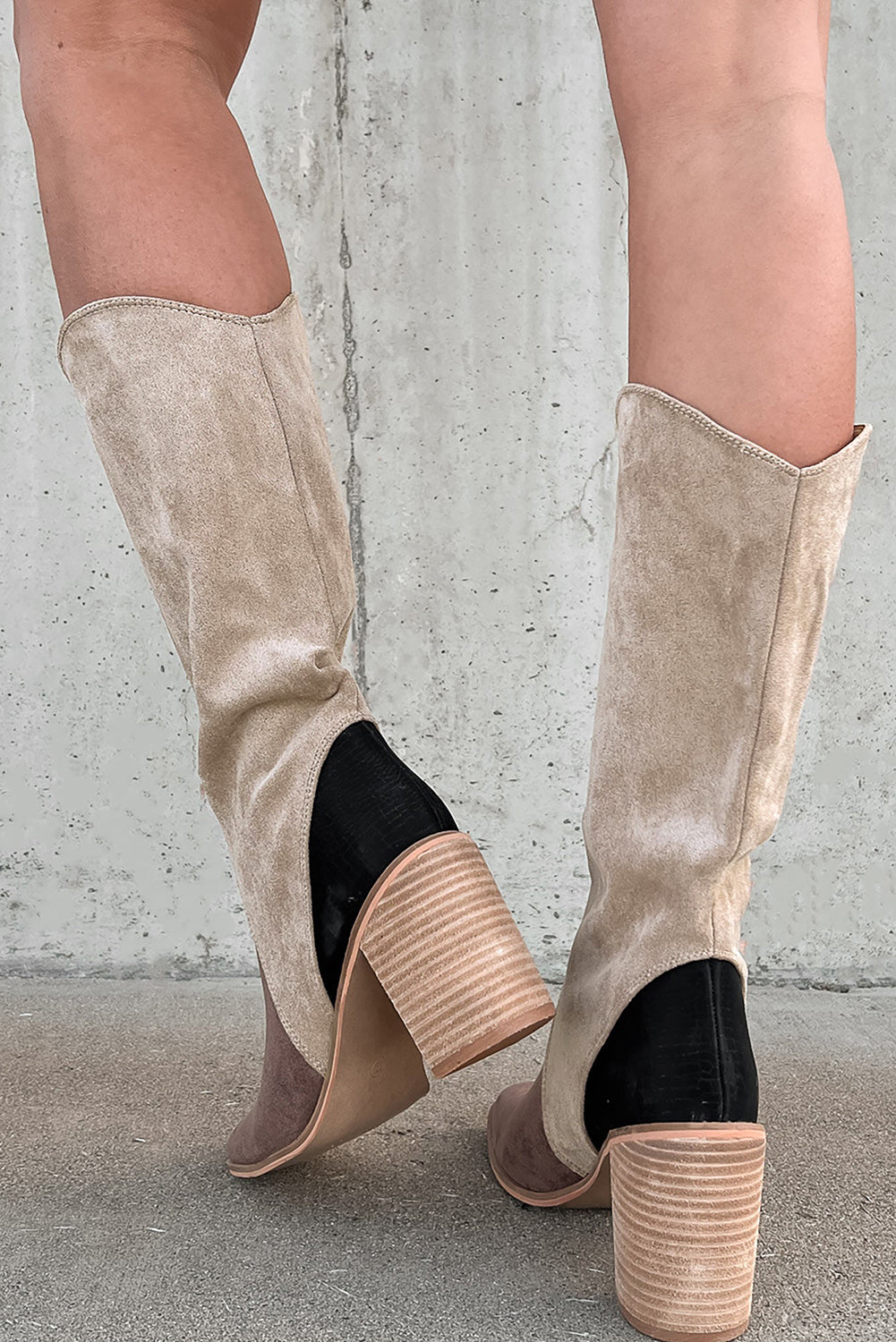 Beige knee-high boots with black accents on a concrete floor.