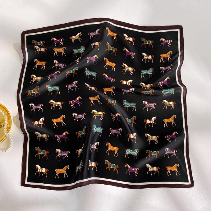 A square silk scarf with a black background, featuring a repeating pattern of colorful horses wearing blankets, finished with a white inner border and a dark brown outer border. It is displayed in a soft drape on a white fabric background.