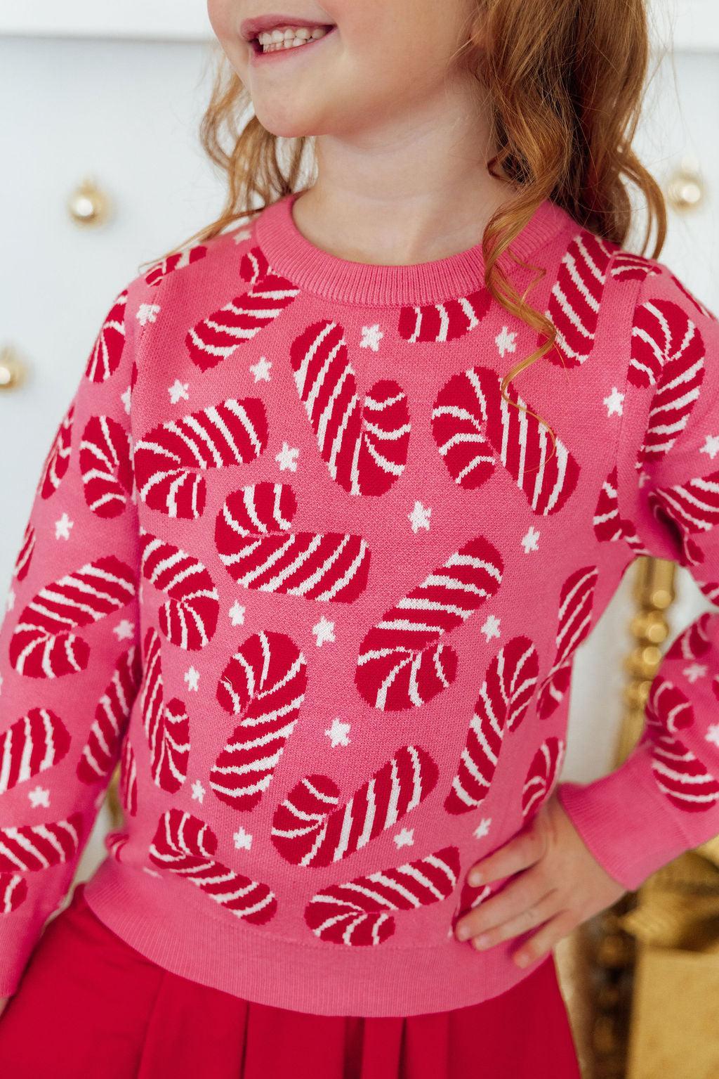 Child wearing a pink sweater with candy cane pattern