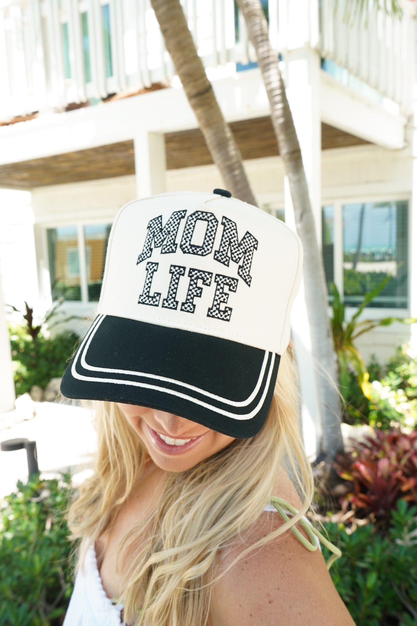 Woman wearing a cap with 'Mom Life' text in an outdoor setting