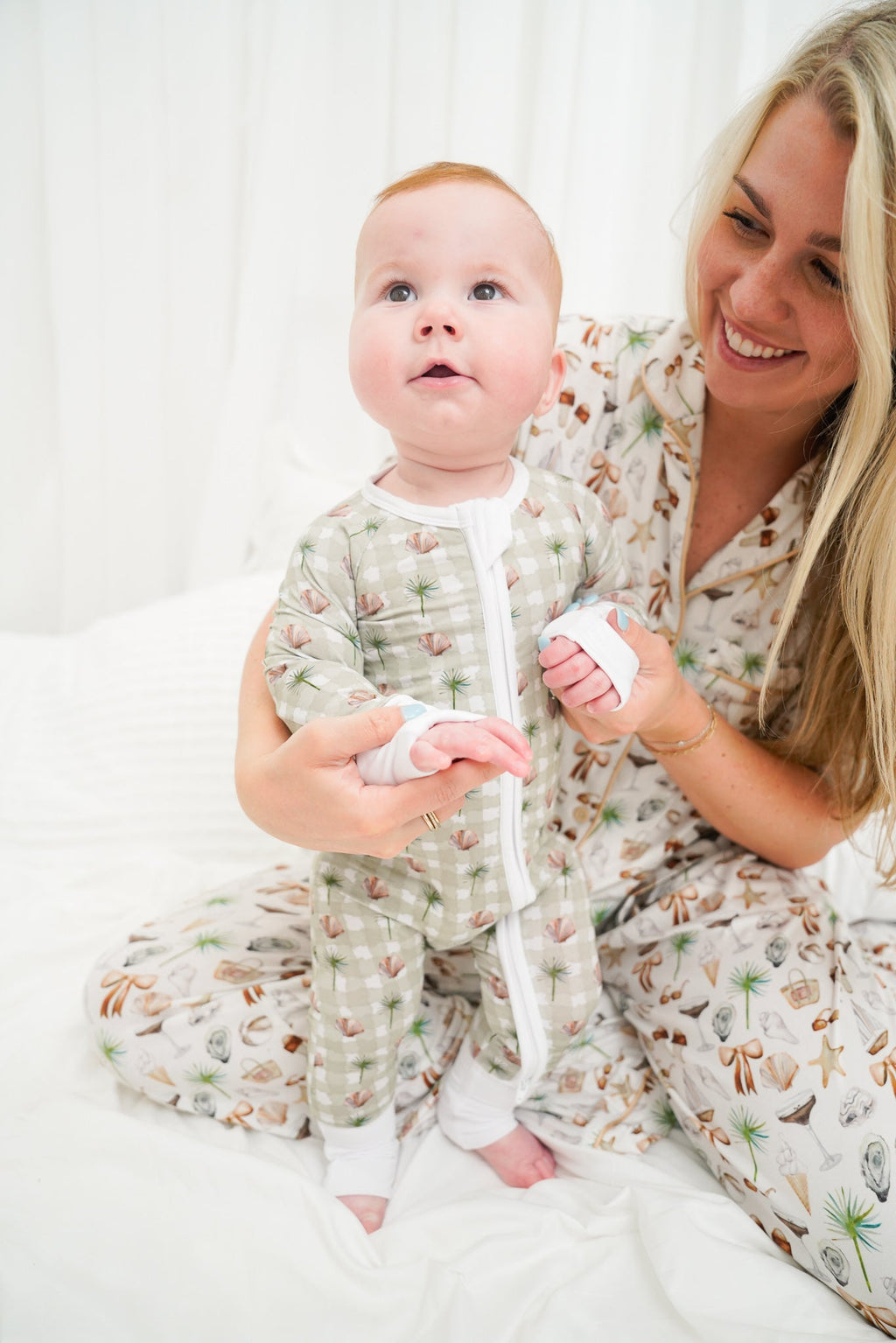 Woman and baby wearing matching pajamas with a white background
