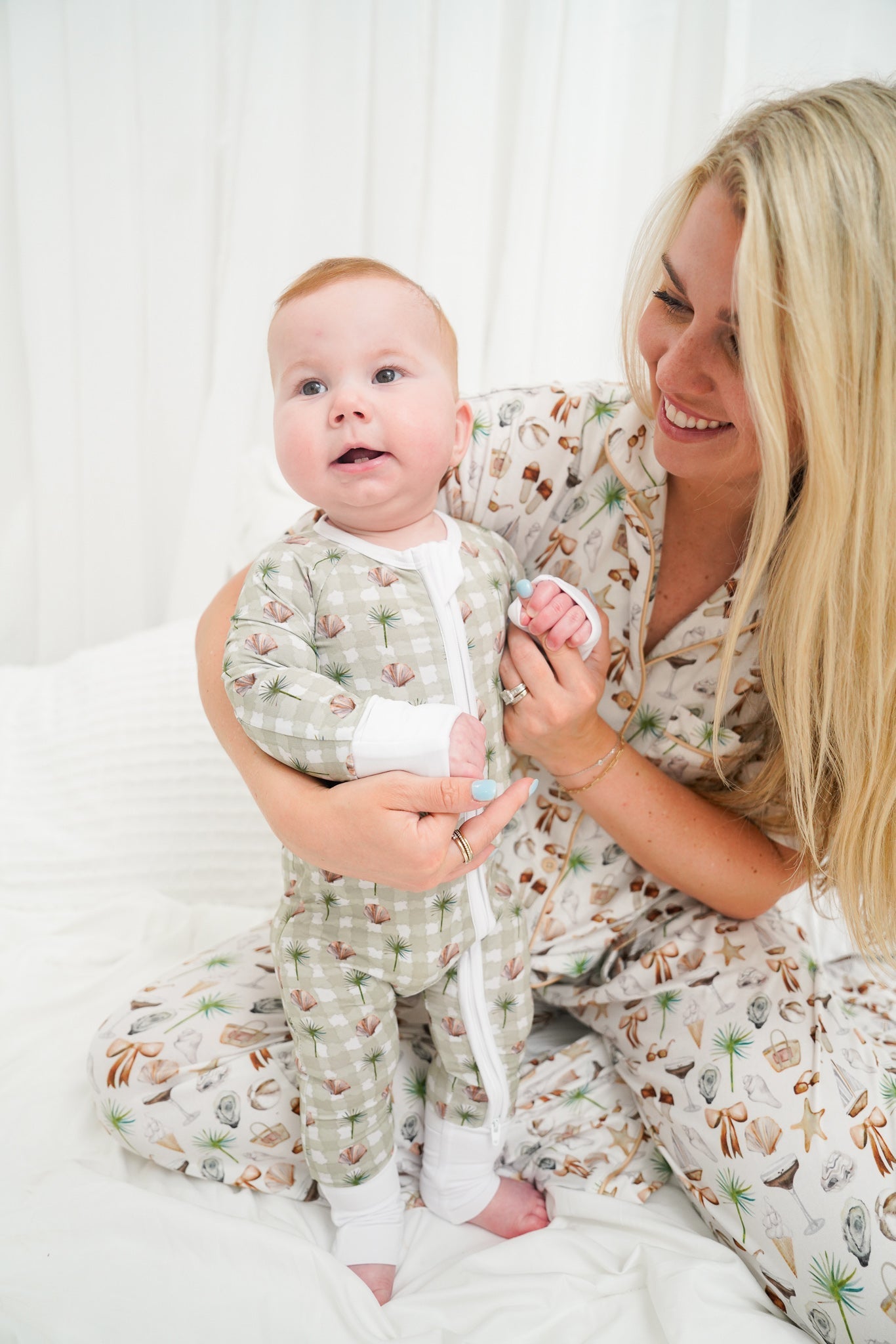 Woman and baby in matching pajamas sitting on a white couch.