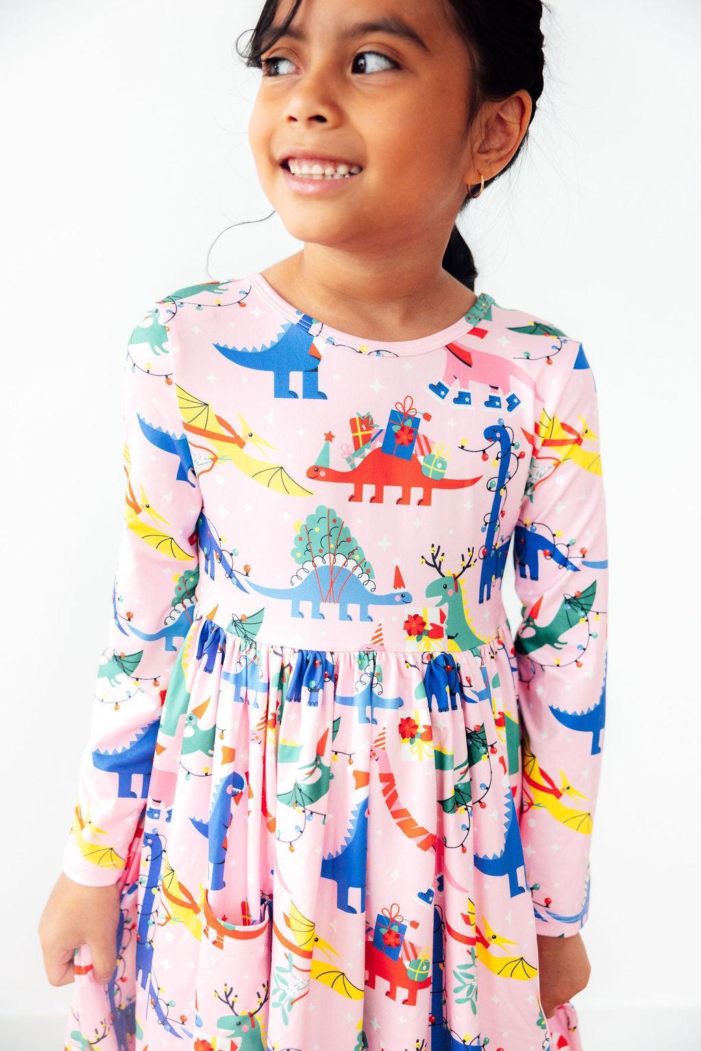 Child wearing a colorful dinosaur-patterned dress on a white background