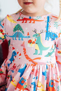 Child wearing a dress with colorful dinosaur patterns on a light background