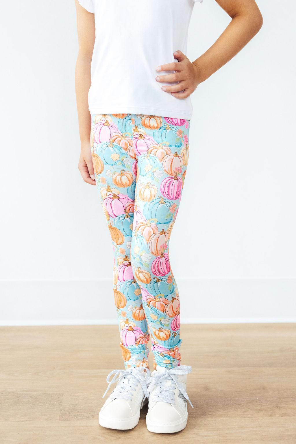 Person wearing colorful pumpkin-patterned leggings on a white background