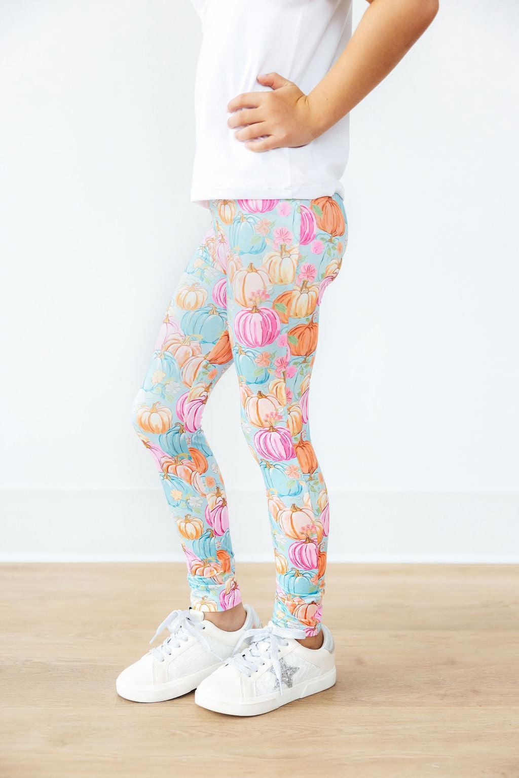 Child wearing colorful pumpkin-patterned leggings on a white background