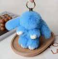 Blue fluffy keychain on a wooden tray with a magazine in the background