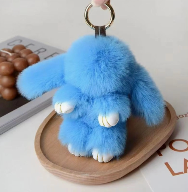 Blue fluffy keychain on a wooden tray with a magazine in the background