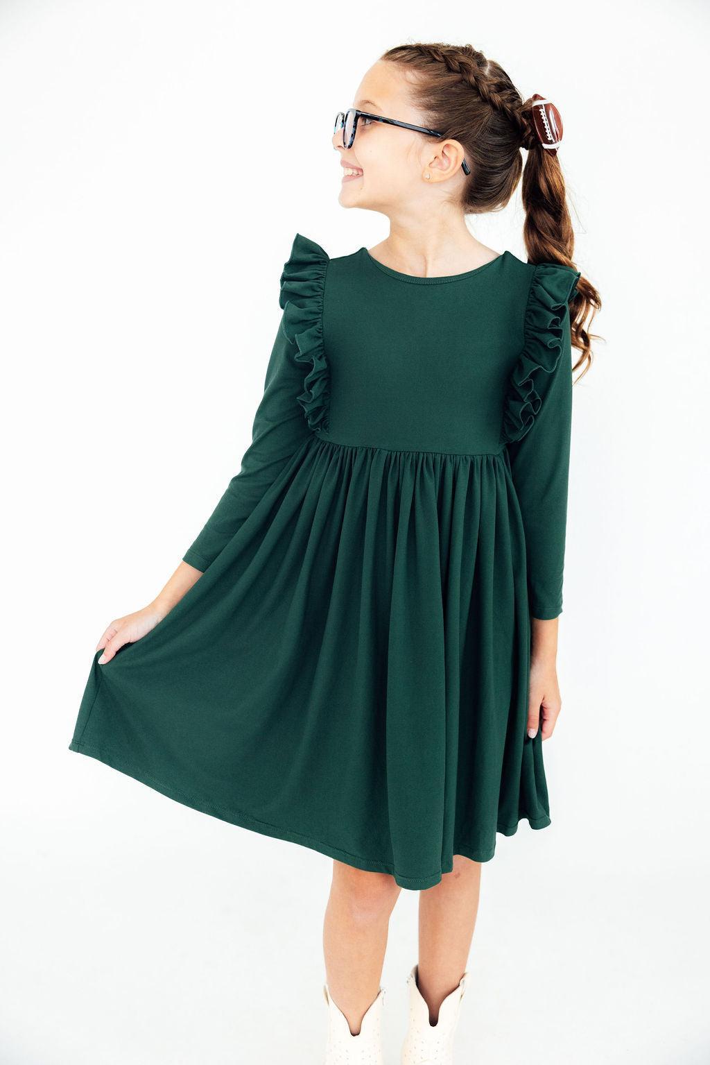 Girl wearing a green dress with ruffled sleeves on a white background