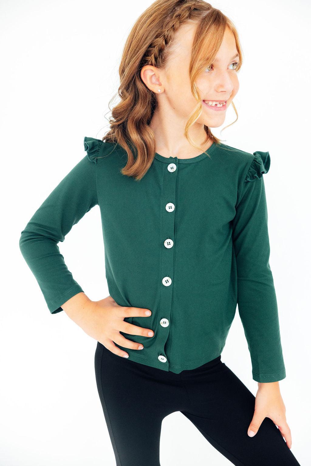 Young girl wearing a green cardigan with ruffled shoulders on a white background