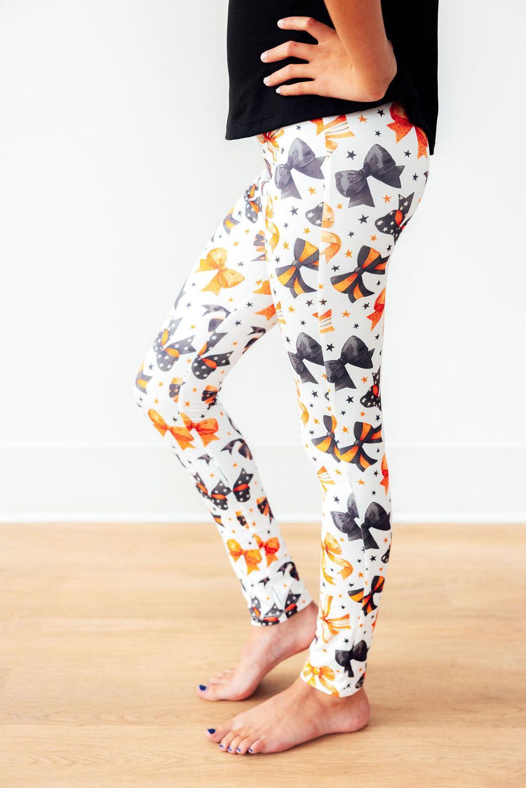 Leggings with colorful cat pattern worn by a person on a light wooden floor.
