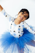 Child wearing a white long-sleeve shirt with black and blue designs and a blue tutu skirt on a white background