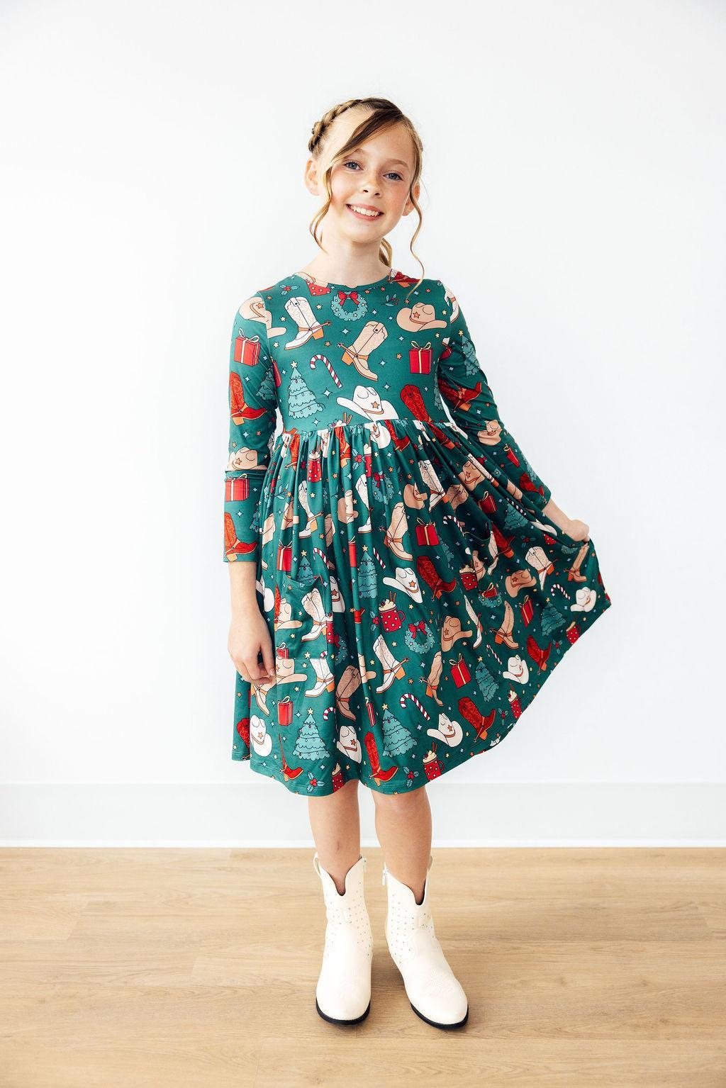 Girl wearing a festive dress with a pattern of Christmas elements on a white background